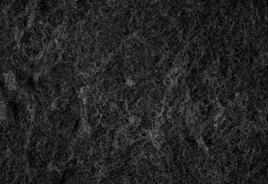 Close-up texture of dark, fibrous material that resembles felt or insulation.