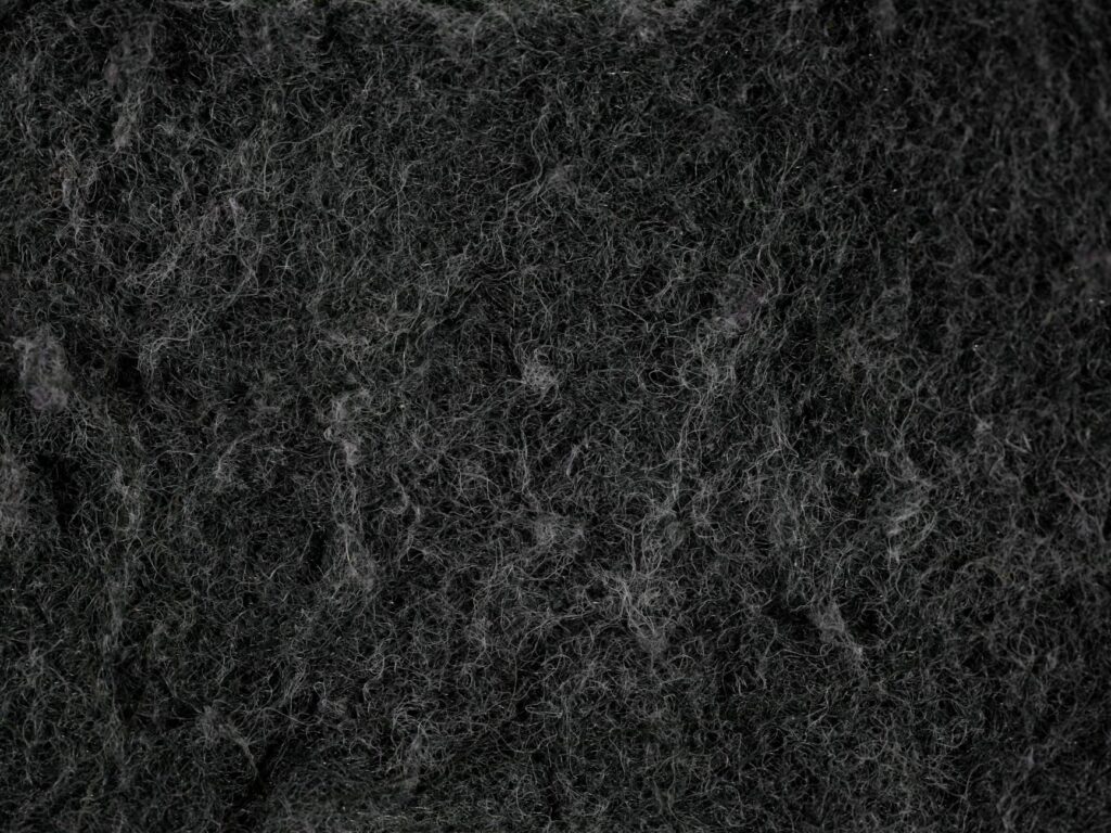 Close-up texture of dark, fibrous material that resembles felt or insulation.