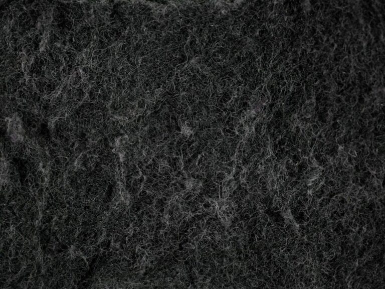 Close-up texture of dark, fibrous material that resembles felt or insulation.