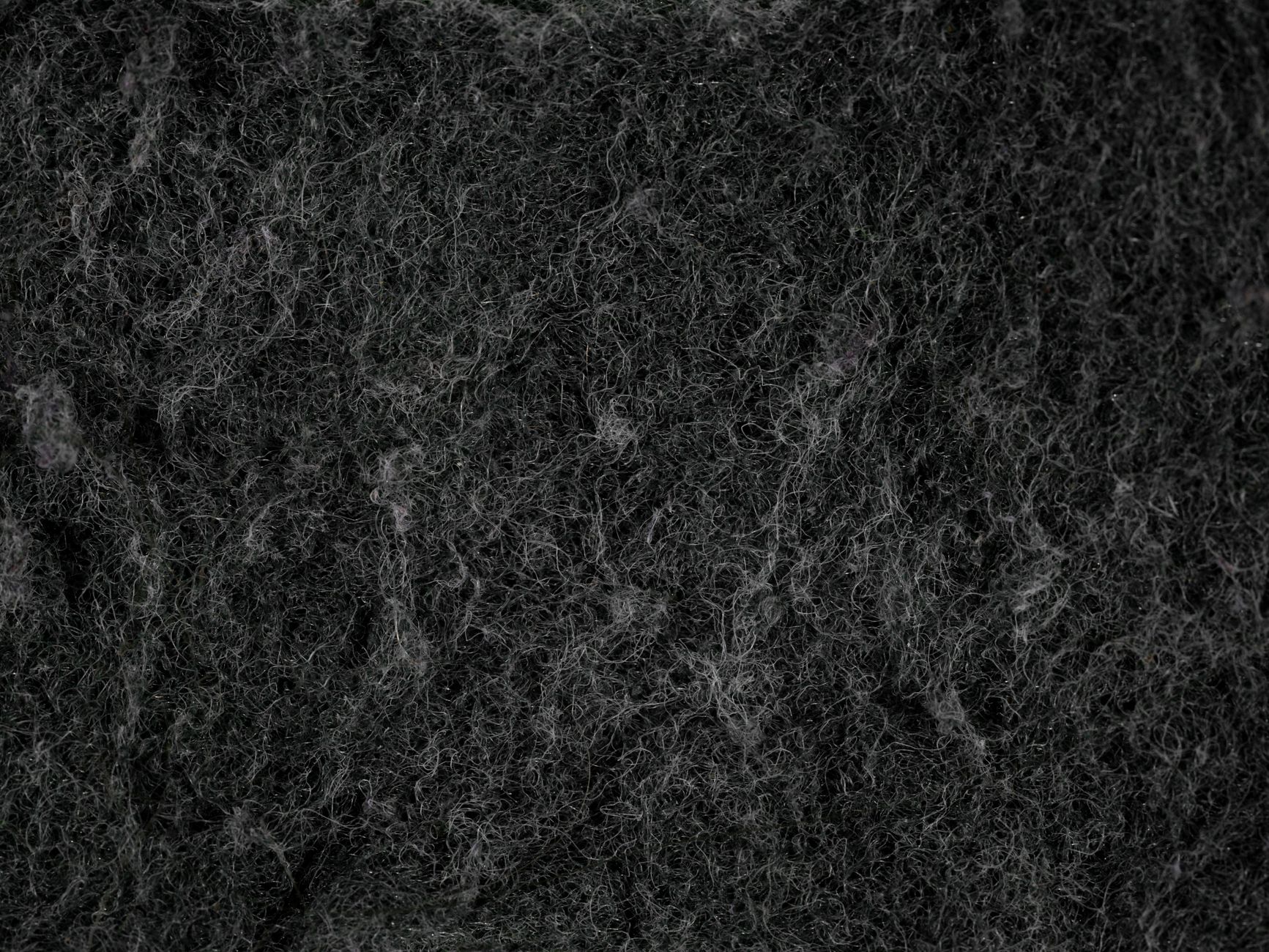 Close-up texture of dark, fibrous material that resembles felt or insulation.